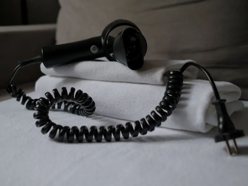 A coiled hair dryer placed on folded white towels, suggesting a hotel setting