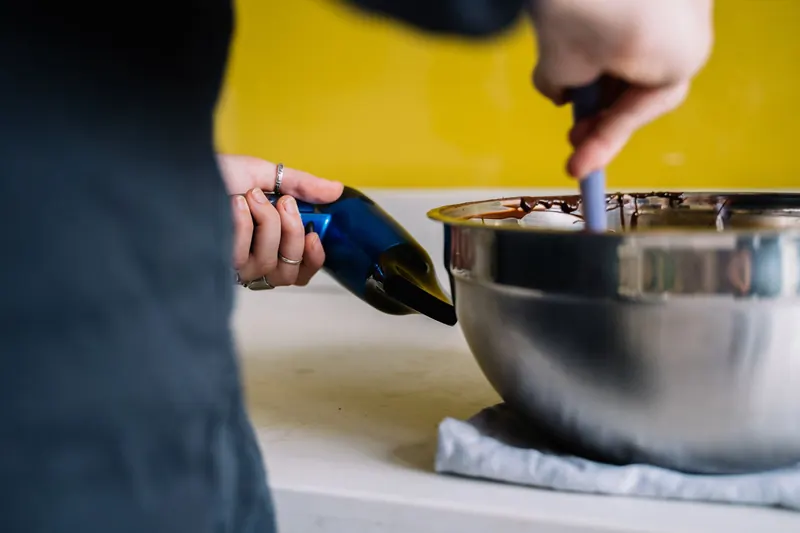 Person melts chocolate in a stainless steel bowl using a hair dryer for a unique cooking method