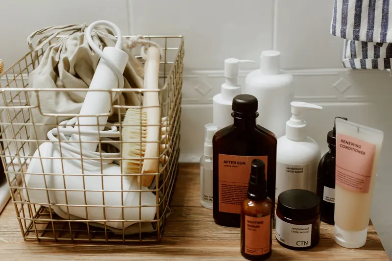 Neatly arranged bathroom toiletries and storage items on a wooden surface, featuring cosmetics and a hair dryer