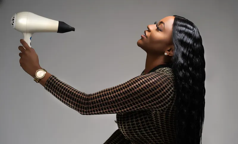 Elegant African American woman in New Orleans blow drying her hair, showcasing modern style