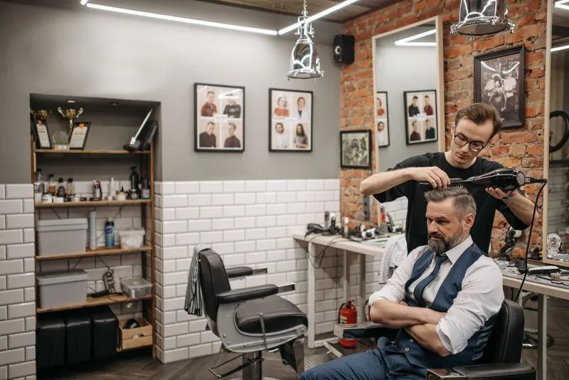 A barber styling a customer's hair in a modern, stylish barbershop setting