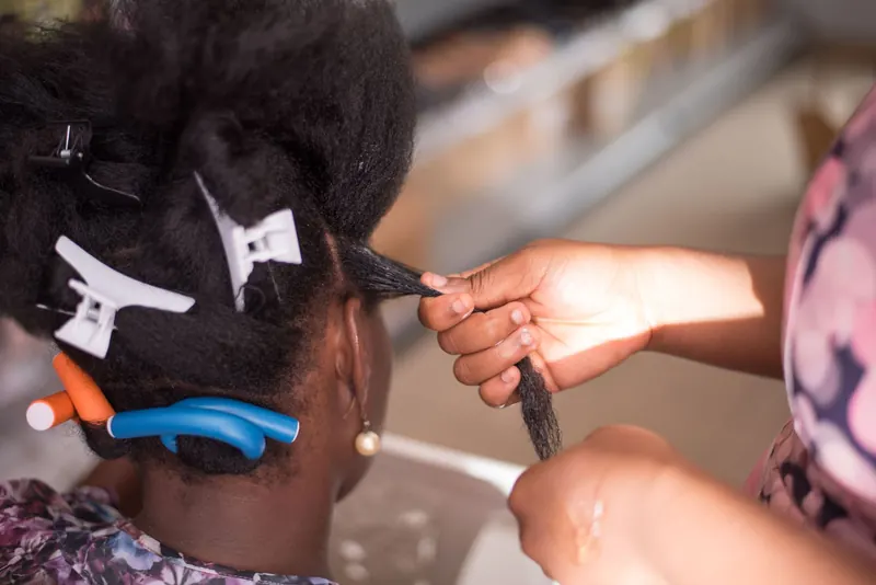 Hairdresser styling a woman's hair with clips in a salon. Close-up of hands and hair