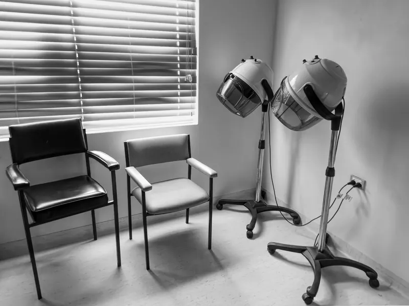 Black and white photo of vintage salon chairs and hair dryers, creating a nostalgic atmosphere